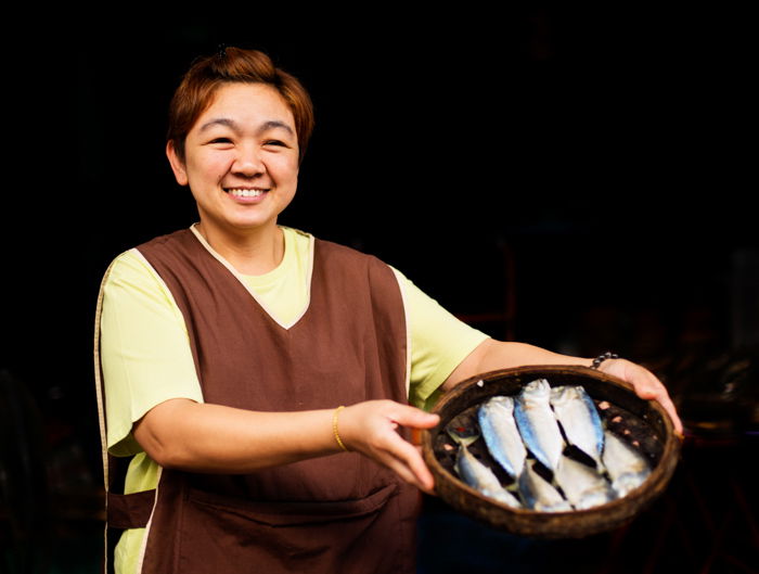 A woman posing with a basket of ish against black background