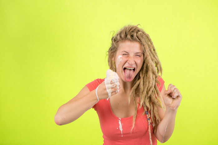 a blond girl eating ice-cream against a bright green background - 