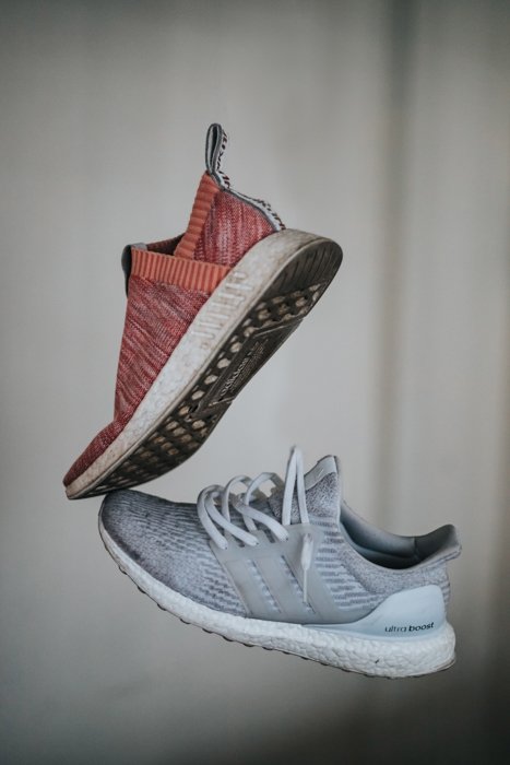 styled photo of red and grey running shoes against a white grey background