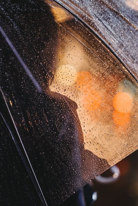Portrait of a person under a rain splatted umbrella