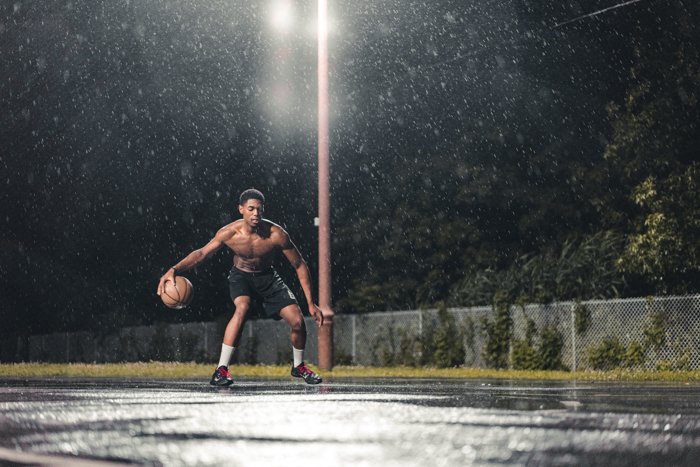 Atmospheric rain photography of a man playing basketball at night