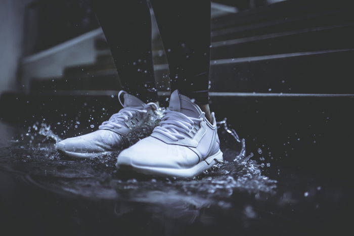 Dark and moody rain image of a persons feet stomping in a puddle shot with fast shutter speed