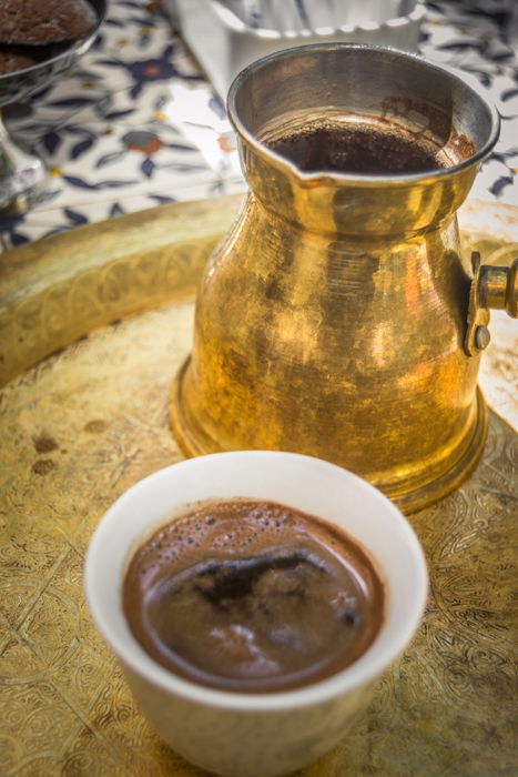 close up of coffee cup and gold metal coffee pot on a gold metal tray