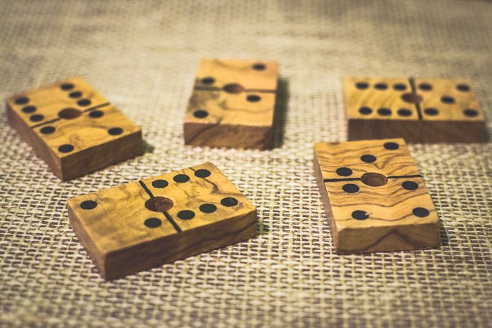 close up of five wood domino tiles on a brown table