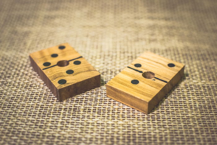 close up of two wood domino tiles on a brown table