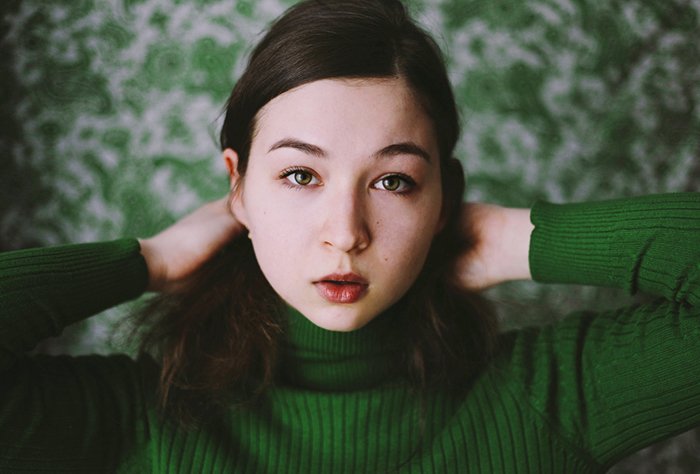 Artistic portrait of a female model posing in green clothes against a green background -creative selfie poses