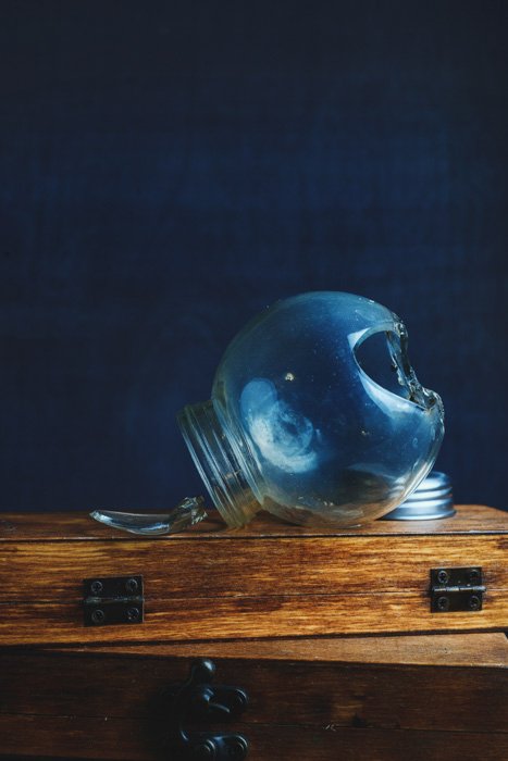 A broken glass spice jar on a wooden box