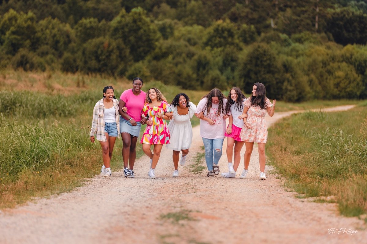 Group of girls walking with arms locked down a country road