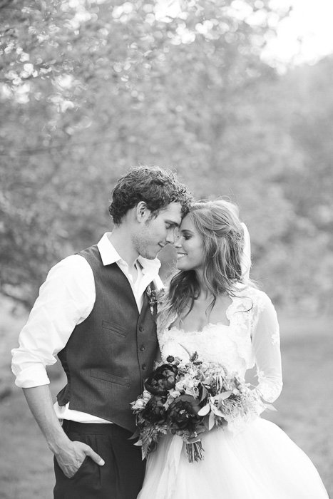 black and white photo of newly weds standing outdoors, gazing into each others eyes, foreheads touching