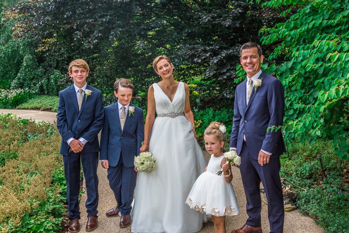 wedding family, bride, groom, and 3 children, standing in a path with bushes and trees behind them, HDR wedding photo editing