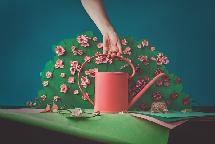 Fun photography still life of a person holding a craft watering can featuring opposite colors red and green