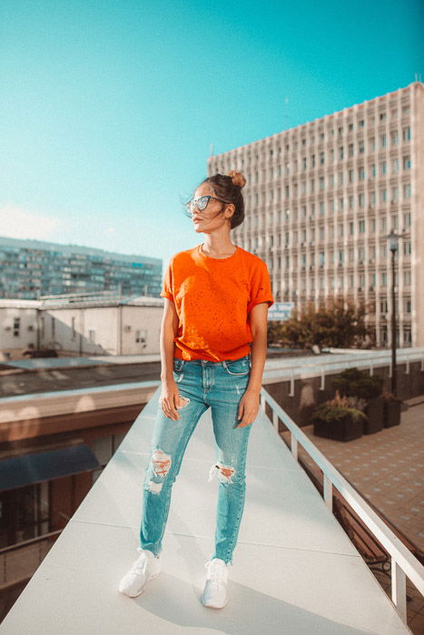 Stylish young woman standing posing on an old wooden staircase. Beautiful  female dressed in a fashionable coat, with a bag holds her hand in her  pocke Stock Photo - Alamy