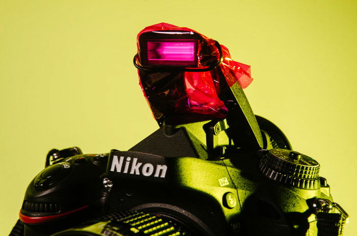 Close up of a Nikon camera with pink cellophane covering the flash - color gel photography