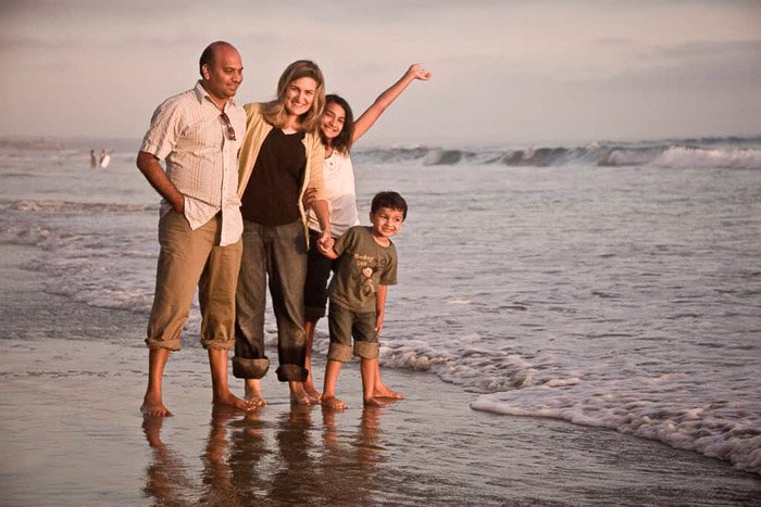A cute family beach pictures shoot with the family walking near the shore in coordinating outfits
