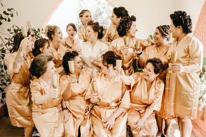 A group photo of a bridal party toasting before a wedding