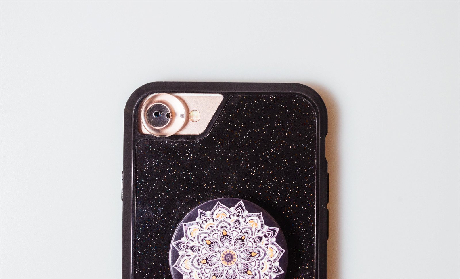 Close-up of a smartphone's camera and black case with a jeweled flowered centrepiece