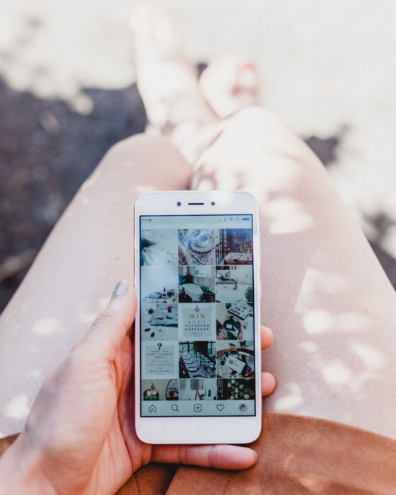 A close up shot of a photographer checking an Instagram page on a smartphone