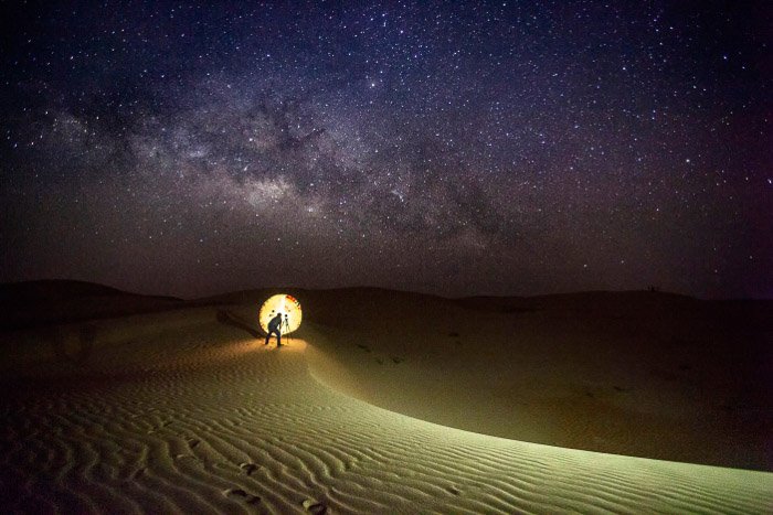 A photographer setting up an astrophotography shot in the desert
