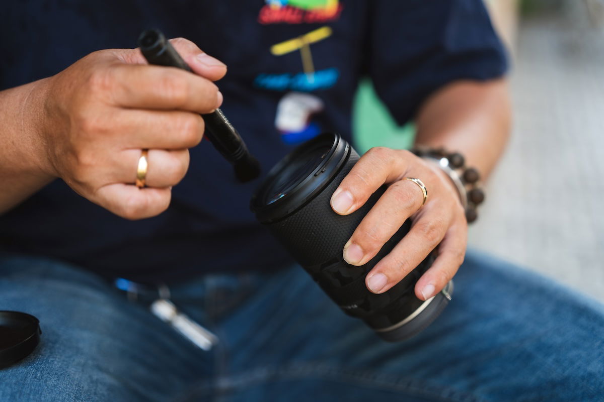 A person cleaning a camera lens to sell camera gear