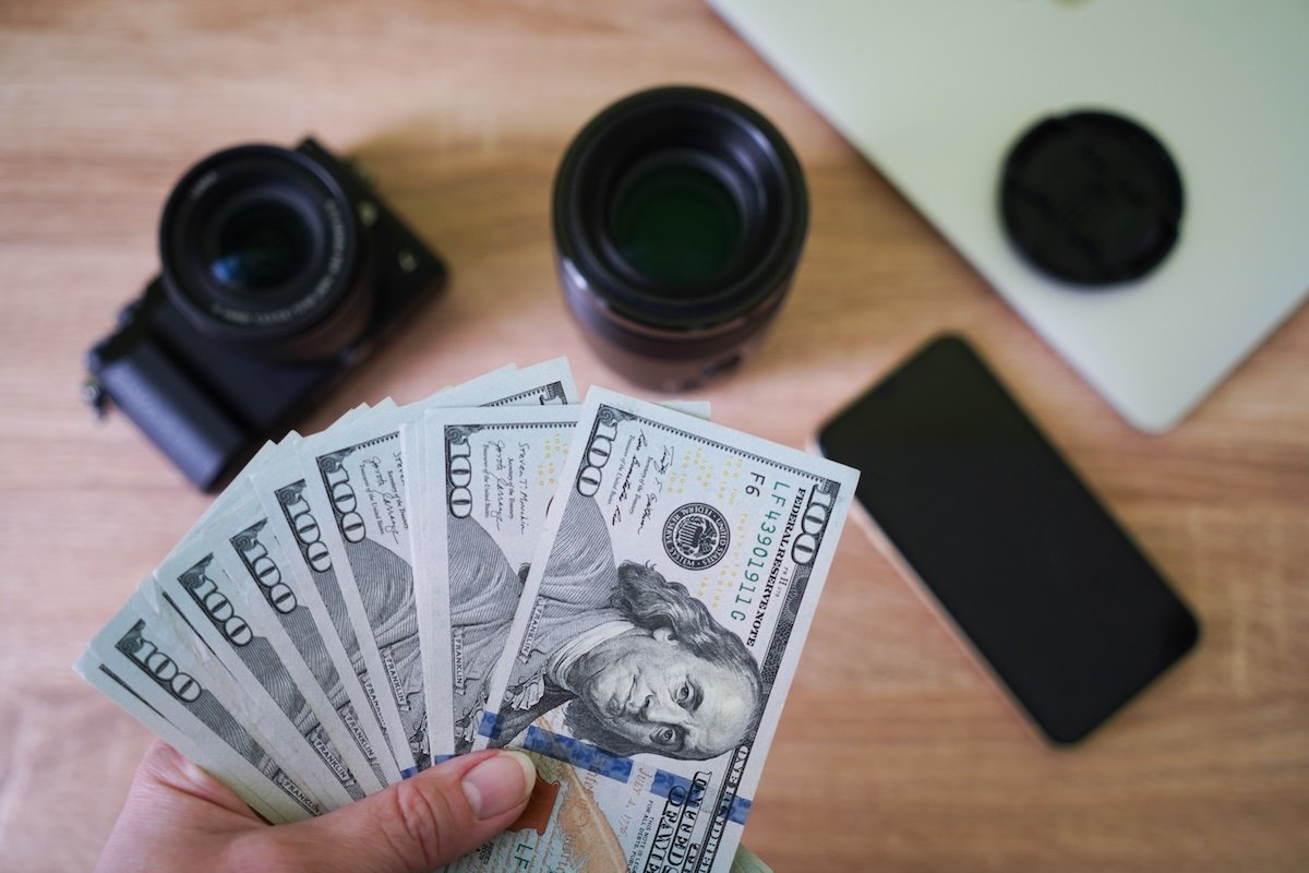A person holding American money to sell camera gear