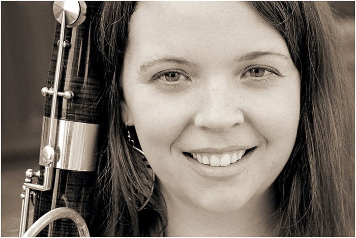 A black and white close up portrait of a female high school senior holding an instrument 