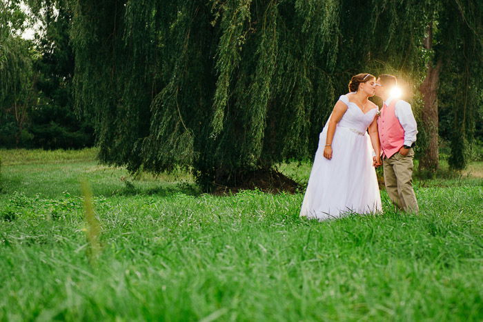 A newly wed couple kissing outdoors, shot with speedlight flash lighting