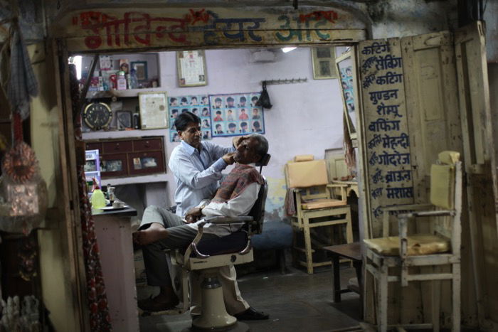 A candid shot of a barber shaving a client - street photography camera settings