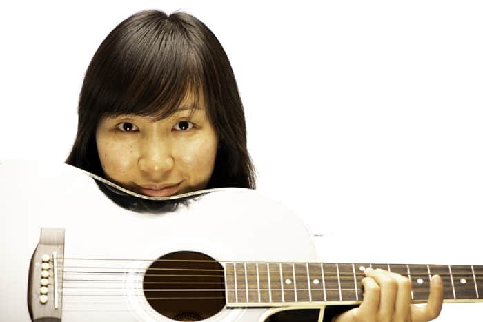 portrait of a female model holding a guitar against a white photography background