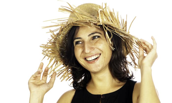 portrait of a female model in a straw hat posing against a white photography background