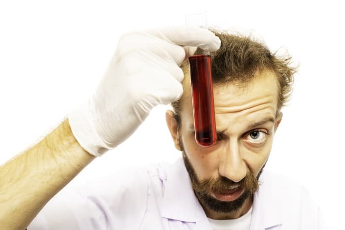 A humourous portrait of a man holding a test tube against a white photo background