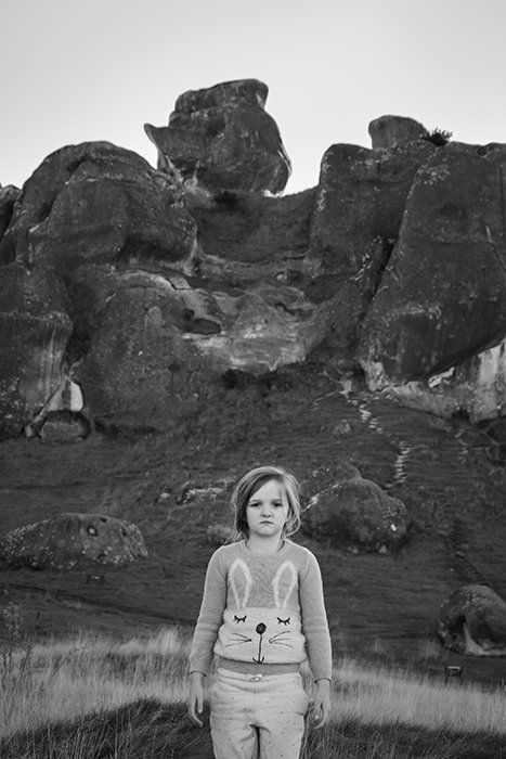 A child posing in front of rocks at at Castle Hill, New Zealand. Black and white photography tips