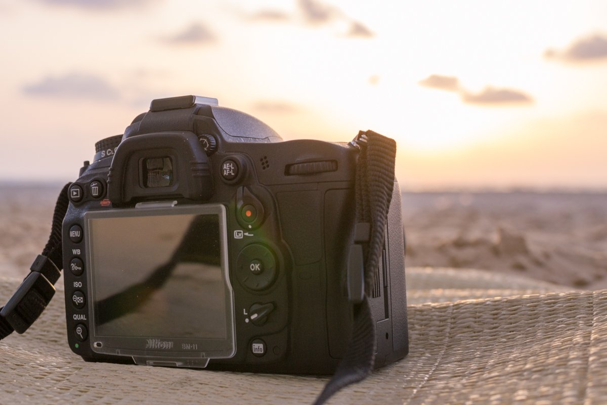 The back of a DSLR camera on a table outside on a beach at sunset