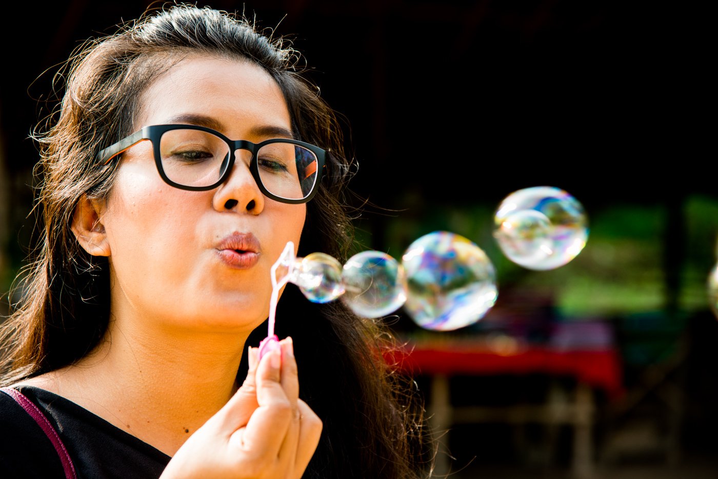 Close-up of a woman blowing bubble outside using rim portrait lighting