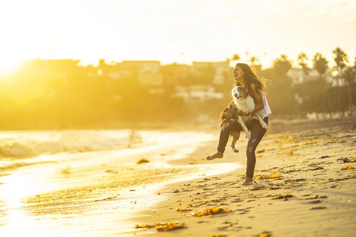 A woman and small dog on a beach shot with a Sony a7R II