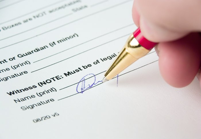 A close up of a photographer writing a model release form for stock photography