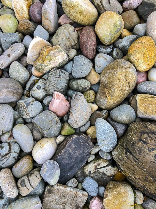 A close up photo of stones and pebbles on the beach