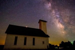 Photo of a small church with the milky way appearing on the night sky