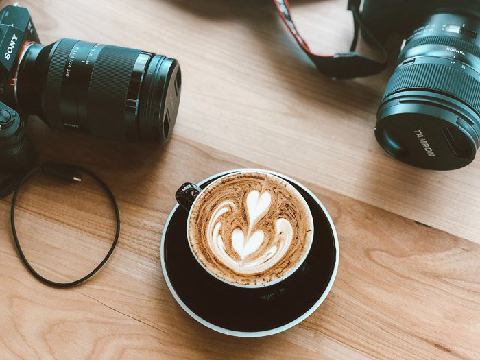 A cappucino on a wooden table with various DSLR camera 