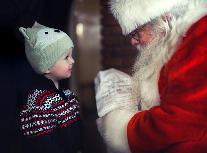An indoor Christmas portrait of a little boy meeting a Santa Claus