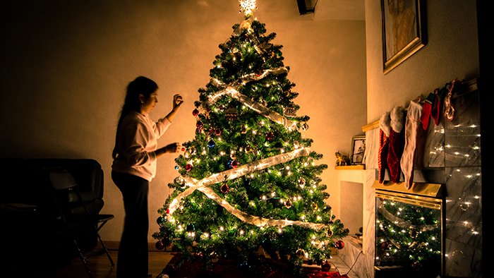 Festive portrait of a woman decorating a Christmas tree
