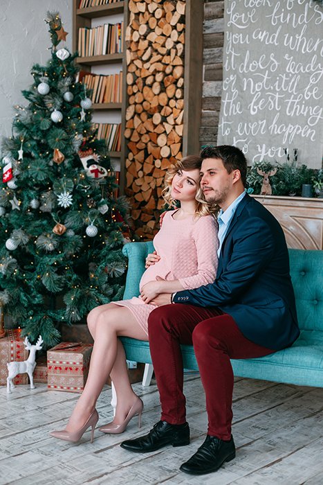 Christmas photo of a couple posing on a sofa by the Christmas tree