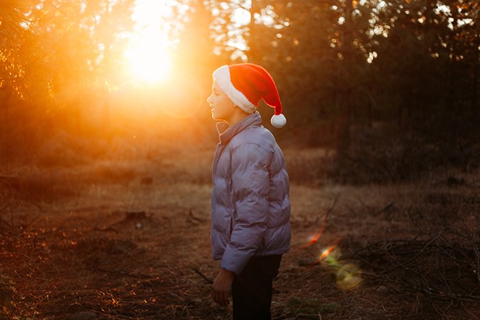 A little boy in a santa hat outdoors