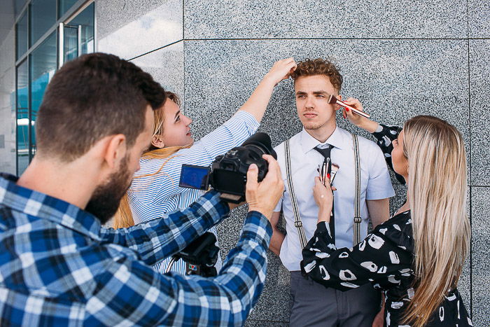 Two stylists attending a male model during a photo shoot