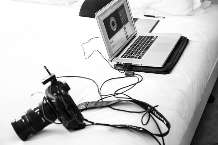 A black and white photo of a DSLR camera attached to a laptop