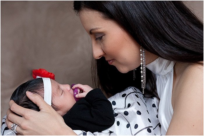 A mother posing with newborn baby for a session at a newborn photography business