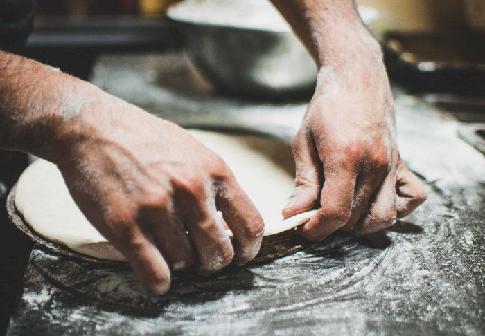 A close up of a person preparing pizza dough