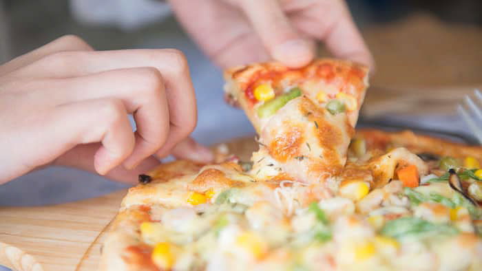 A close up of a person taking a slice of pizza