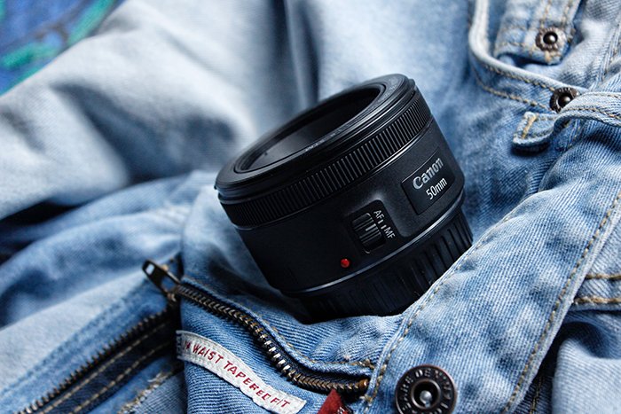 A Canon 50mm prime lens for pet photography resting on a denim jacket