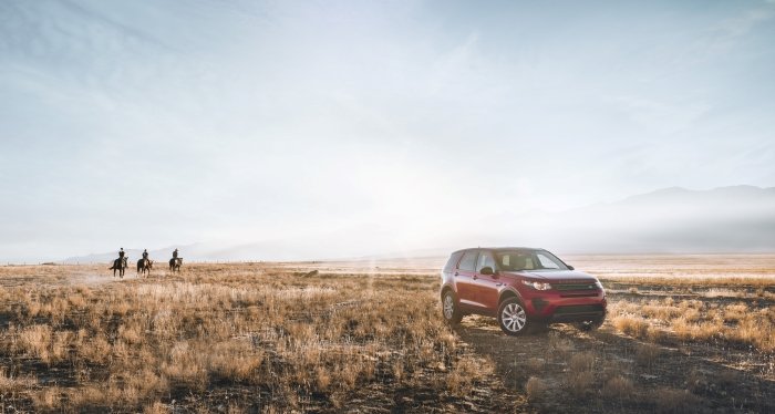 Product photo of a car in a country landscape with people on horses
