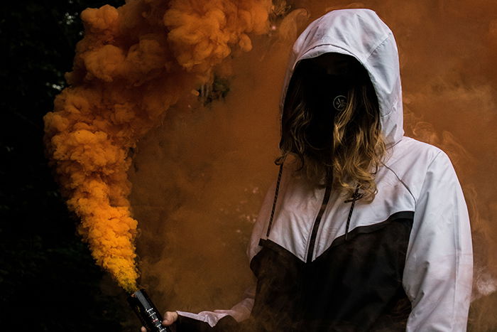 Faceless portrait of a woman holding orange smoke grenades